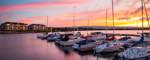 long panorama aspect ratio image of the harbour and the sunset toward Blue Mountain with light glowing off the shipyards development by the water.